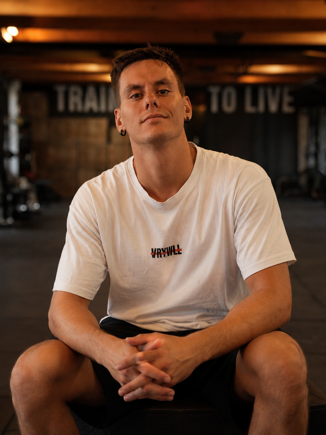 Coach Very Well seduto in sala sotto la scritta "Train to Live"